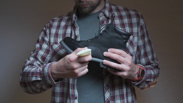 A person treats a leather boot with conditioner, focusing on cleaning and preserving the material. The scene highlights practical footwear care and maintenance.