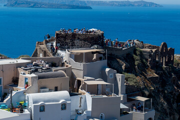 Santorini, Greece - 11.06.2026: Crowds gather on Oia Castle ruins above whitewashed buildings with Aegean Sea and caldera views. © Andrei Tomas