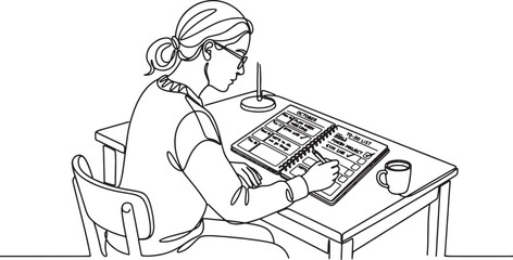 Fototapeta premium woman sitting at a desk writing in a notebook with a cup of coffee