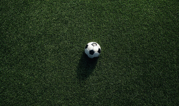 A classic black and white soccer ball resting on a textured green artificial grass surface, captured from a angle down perspective view