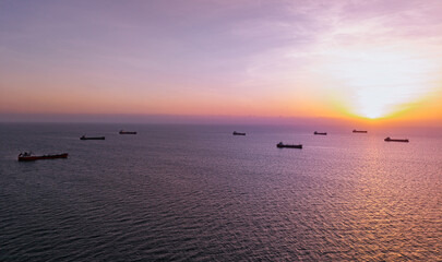 Cargo ships anchored at sunset over open ocean waters © Parilov