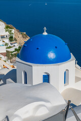 Whitewashed Greek Orthodox chapel with blue dome above the caldera and deep blue water in Santorini, Greece. © Andrei Tomas