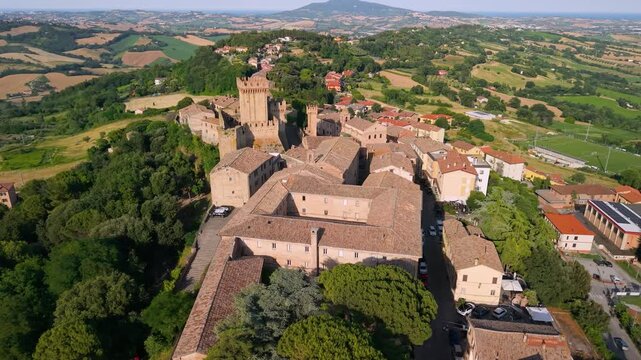 Offagna Marche Italy 4K Aerial. Drone flight along medieval fortress castle walls and towers on ridge. Authentic Italian borgo townscape on rolling green hills background. I Borghi pi&ugrave; belli d'Italia