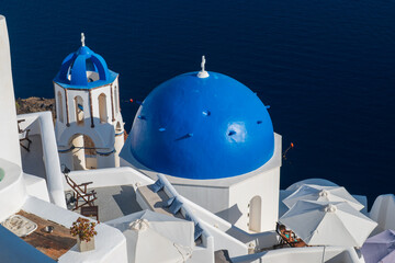 Iconic whitewashed architecture with blue domes and sea view on Santorini, Greece, in bright summer sunlight. © Andrei Tomas