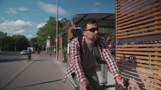 A cyclist rides along a modern two-level bicycle parking area near a metro station in Munich, Germany, searching for a free spot. Contemporary urban mobility and organized cycling infrastructure.
