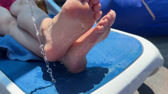 Prank on sunbathing woman: pouring water on her feet while she rests, playful splash, surprised reaction.