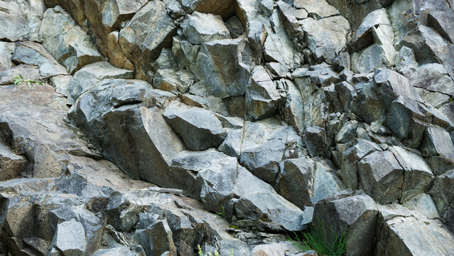 A detailed shot of a rugged, grey rocky mountain side with sharp edges and natural cracks, perfect for nature and adventure designs