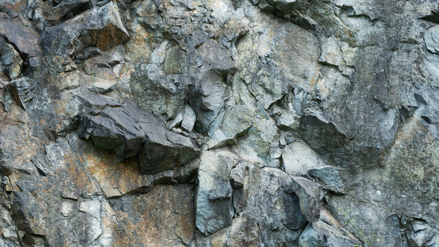 High-resolution close-up of a natural, rugged granite rock face with sharp textures, crevices, and earthy tones suitable for backgrounds or design elements.