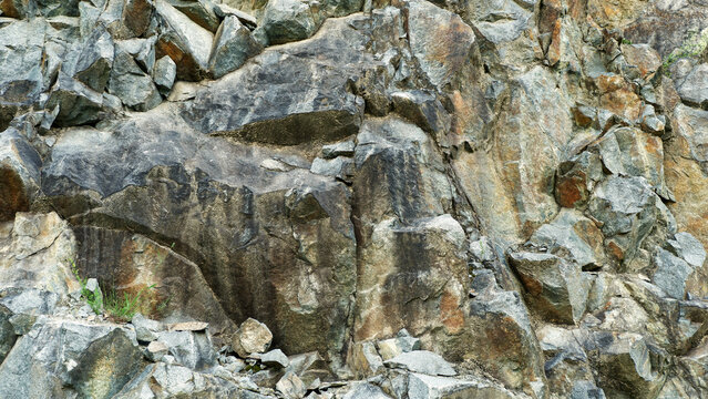 A dramatic, dark-toned close-up of a granite rock face, perfect for textured backgrounds requiring a sense of geological depth and ruggedness.