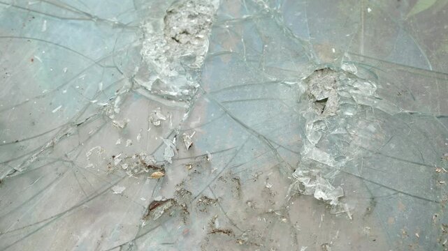 Cracked glass surface with impact marks and shattered texture representing damage and destruction