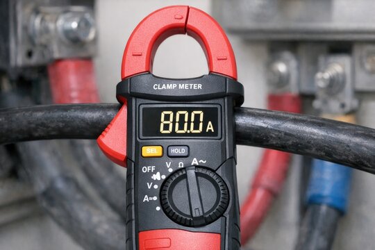 A clamp meter on a wire with wires in the background