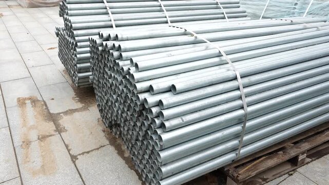 Stacked galvanized steel fence pipes prepared for installation at construction warehouse for infrastructure and roadside fencing system