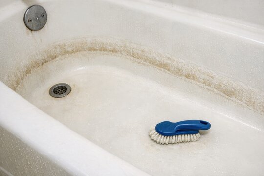 A blue brush sits alone in a bath tub