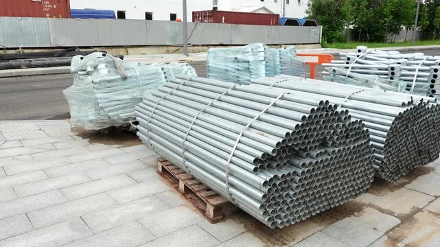 Stacks of galvanized metal pipes stored at construction site, concept of engineering infrastructure and industrial materials supply