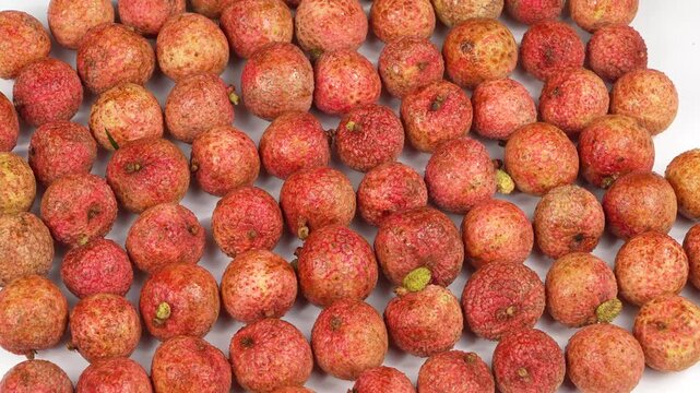 Full frame macro texture background of fresh glossy red lychee fruits wet with water