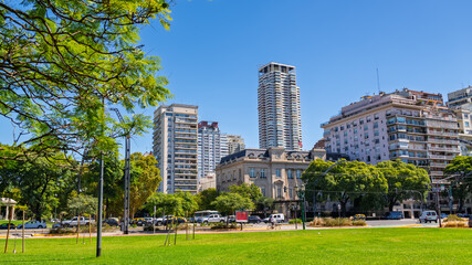 Obraz premium Buenos Aires, Argentina - - MARCH 17, 2026: Modern skyscrapers and classic French-style architecture seen from a lush green public park in the Palermo district on a sunny day