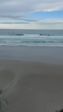 High angle view of human footprints on wet sand with ocean waves crashing on Os Castros beach Ribadeo