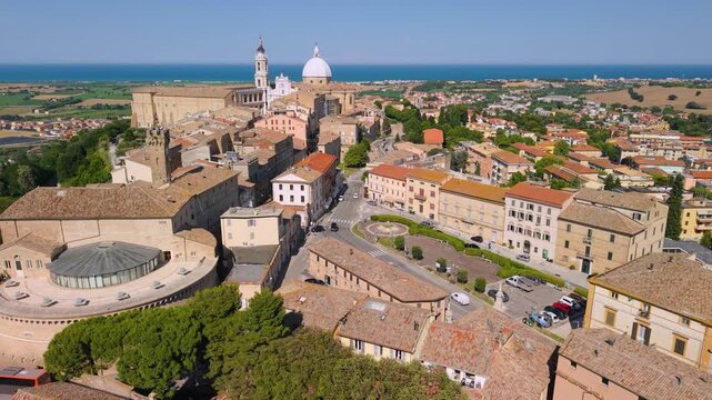 Loreto Marche Italy 4K Aerial. Old town center drone panorama of basilica dome and historic fortress towers with blue sea background. Authentic Italian borgo secret travel hidden gems asset