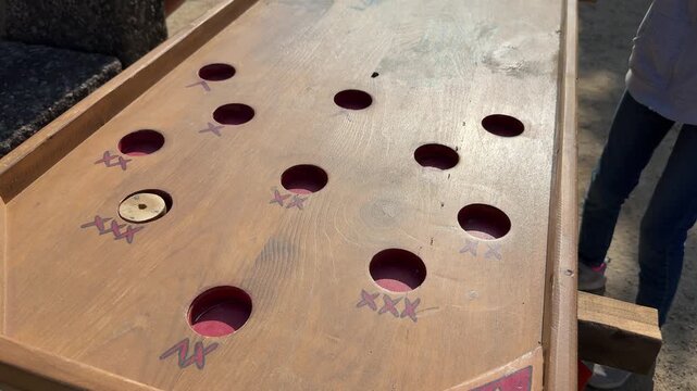 Wooden tabletop game with holes, outdoor fair entertainment close up