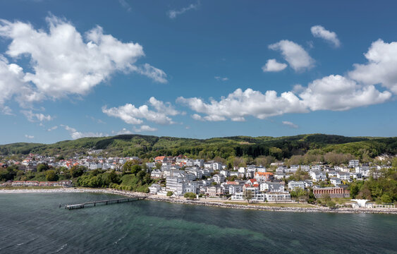 Wide aerial panorama of Sassnitz in Mecklenburg-Vorpommern, Germany, featuring the harbor, waterfront town, Baltic shoreline, and coastal landscape on Ruegen island.