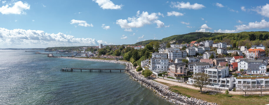 Panoramic coastal view of Sassnitz, Mecklenburg-Vorpommern, Germany, with harbor infrastructure, town buildings, Baltic waterfront, and the green shoreline landscape.
