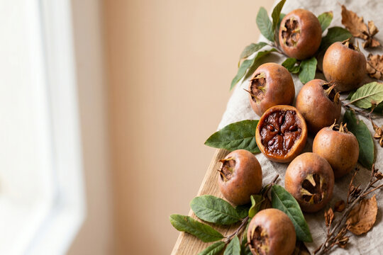Organic ripe medlar fruits with green leaves on a rustic wooden table
