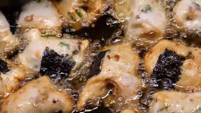 Close up video of traditional Korean fish cakes wrapped in a sheet of seaweed nori deep frying in hot boiling oil. Golden brown crispy savory street food snack popular in Asian night markets