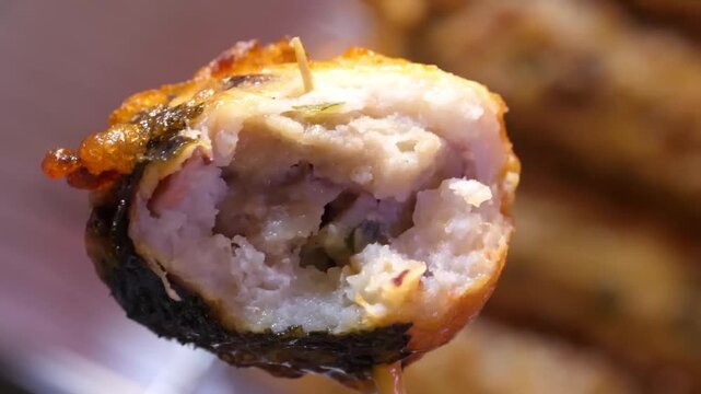 close-up shot of a savory, deep-fried Korean fish cake bar (eomuk bar) wrapped in dark nori seaweed, bitten open to show the soft, steaming texture inside on a wooden toothpick skewer. Perfect for Asi
