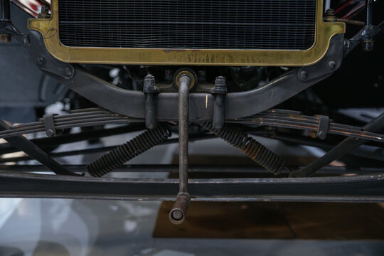 The front suspension and radiator assembly of a historic automobile are displayed in detail. The image showcases early vehicle construction and engineering design.