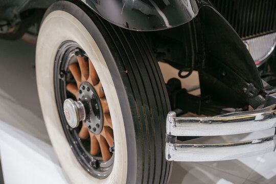 Close up of a whitewall tire and wheel on a vintage automobile. The classic vehicle features historic styling and restored automotive details.