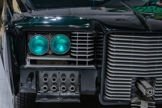 Detailed close up of custom headlights and front grille on a modified automobile. The vehicle showcases unique automotive styling and design features.