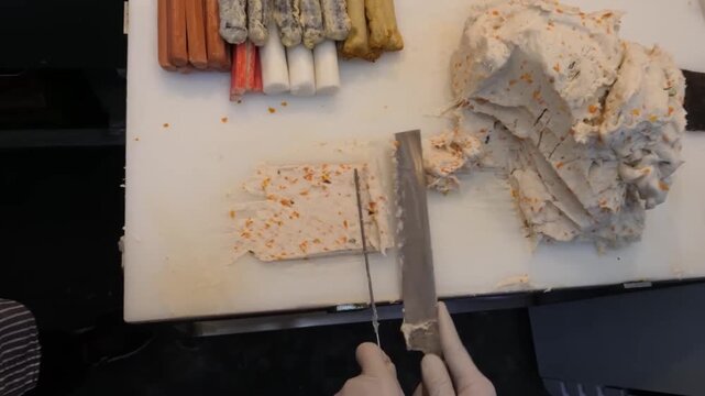 High-angle footage of a master chef preparing authentic Korean handmade fish cakes (Eomuk). The scene features a large batch of seasoned fish paste dough being sliced and shaped on a white prep table 