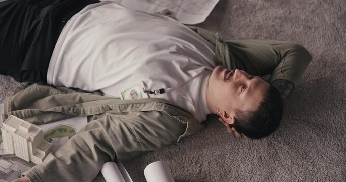 A person is lying on the floor in a room. Food containers are around them on the carpet