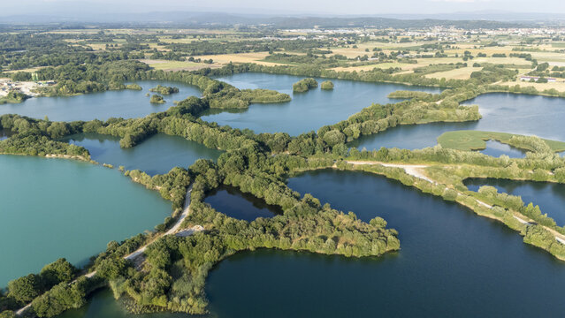 Aerial view of Lagoa de Antela featuring interconnected ponds with lush green vegetation and clear blue water surrounded by agricultural fields in Ourense, Ourense, Spain.