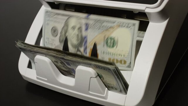 Money counting machine processing dollars bills in motion. Business finance theme. Device counting paper money in motion. Counting cash concept. Banking operation.