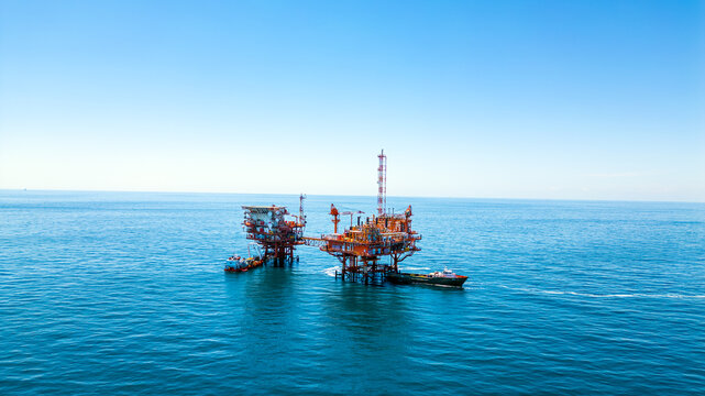 Aerial view of an offshore oil rig platform in the Adriatic Sea with a support vessel nearby under a clear blue sky in Croatia.