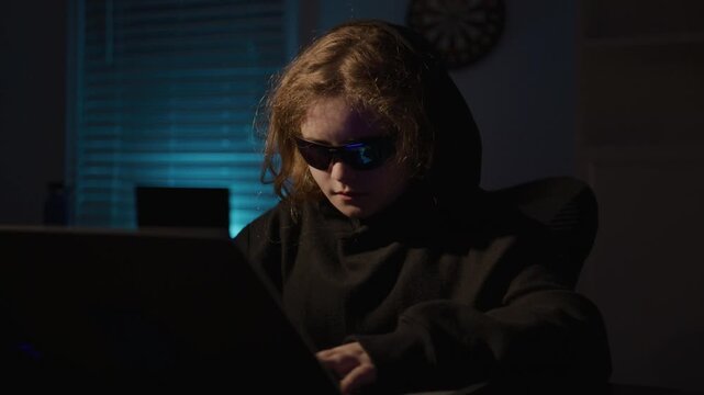 Hacker kid using a laptop. Kid hacker typing on laptop. Child hacker learning coding on laptop. Young hacker kid with laptop.