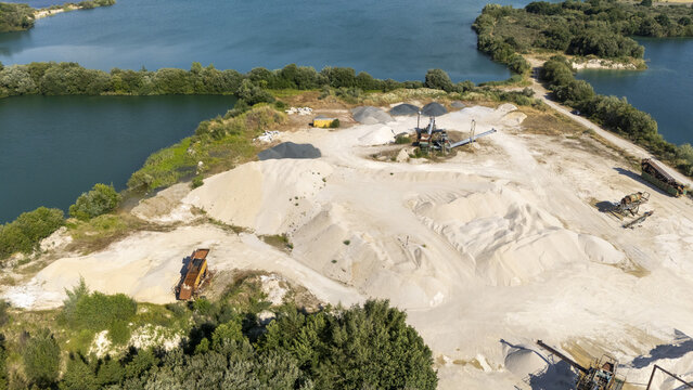 Aerial view of the Extraccion de aridos Lima SL quarry, with piles of sand, gravel, industrial machinery, and surrounding water bodies in Vilarino das Poldras, Ourense, Spain.