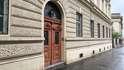 Fototapeta premium Historic European Building Facade With Ornate Entrance Door, Decorative Stonework And Classical Urban Architecture On Quiet City Street