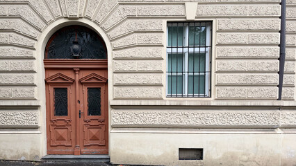 Fototapeta premium Historic European Building Facade With Ornate Entrance Door, Decorative Stonework And Classical Urban Architecture On Quiet City Street
