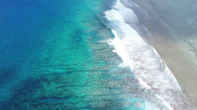 A drone view of Rarotonga, the capital of the Cook Islands.Ocean waves crash on shore and reveal patterns in the water during the daytime at a tropical beach