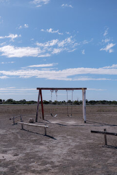 An empty wooden swing set sits in a desolate, dry field crossing the Nullarbor Plain