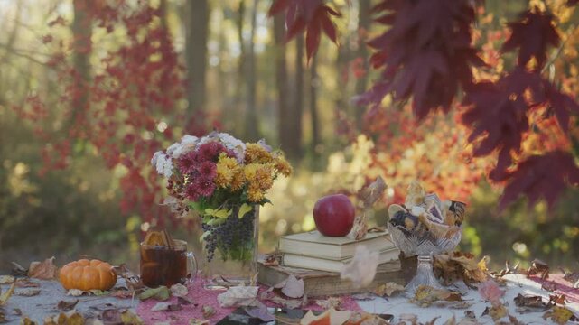 Autumn still life on table. Warm fall comfort scene. Autumn table with apple and books. Cozy outdoor fall moment. Autumn leaves framing table. Warm seasonal table setup.