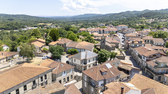 Aerial view of the historic town of Allariz with traditional stone buildings, terracotta rooftops, and narrow streets surrounded by lush green hills in Allariz, Province of Ourense, Spain.