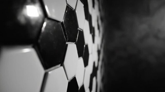 Black and white soccer ball pattern close up with cinematic lighting and a dark background for sports related content.