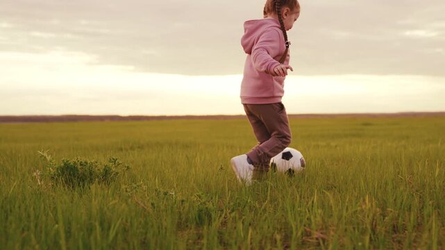 Girl playing soccer at sunset, The golden field is calm, The sky is glowing, She is alone, Her hair is braided, A soccer ball is at her feet, She wears pink clothes, The grass is green, Peace fills