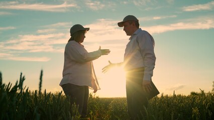 Business people working in rural area. Farmers, shake hands, work together with tablet, sign contract in wheat field, sun. Teamwork business partners. Man woman shake hands in field. Agricultural © Victoriia