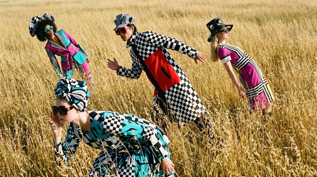 Group of models in bold fashion designs posing in a field during daytime in summer