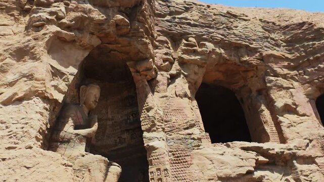 Yungang, China - May 9 2026: A monumental cliffside face of the Yungang Grottoes, showcasing ancient, intricately carved Buddhist caves, majestic colossal statues, and historic wooden temple facades