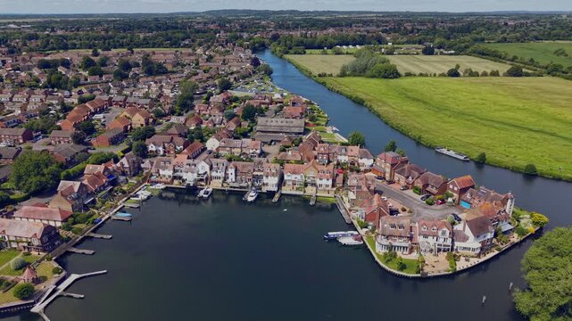 Cinematic aerial drone footage of Abingdon Marina in Oxfordshire, England, showing moored boats, marina docks, and the River Thames surrounded by green landscapes on a bright sunny summer day